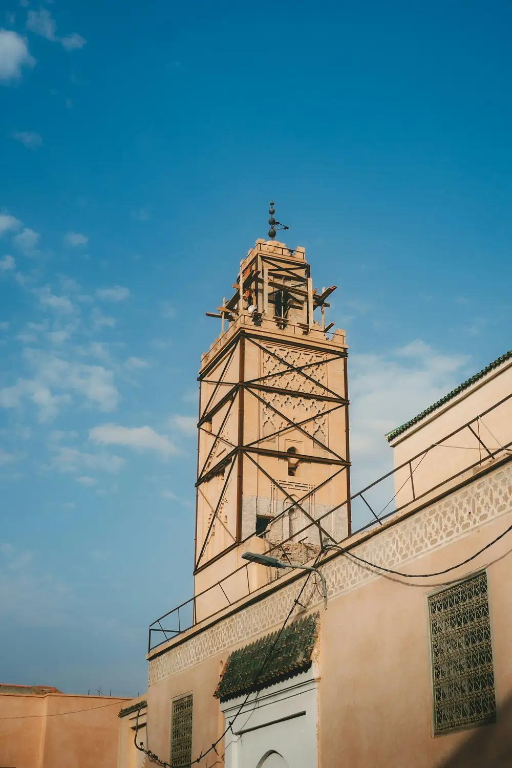 Minaret d'une mosquée aux façades ocre, sous un ciel bleu