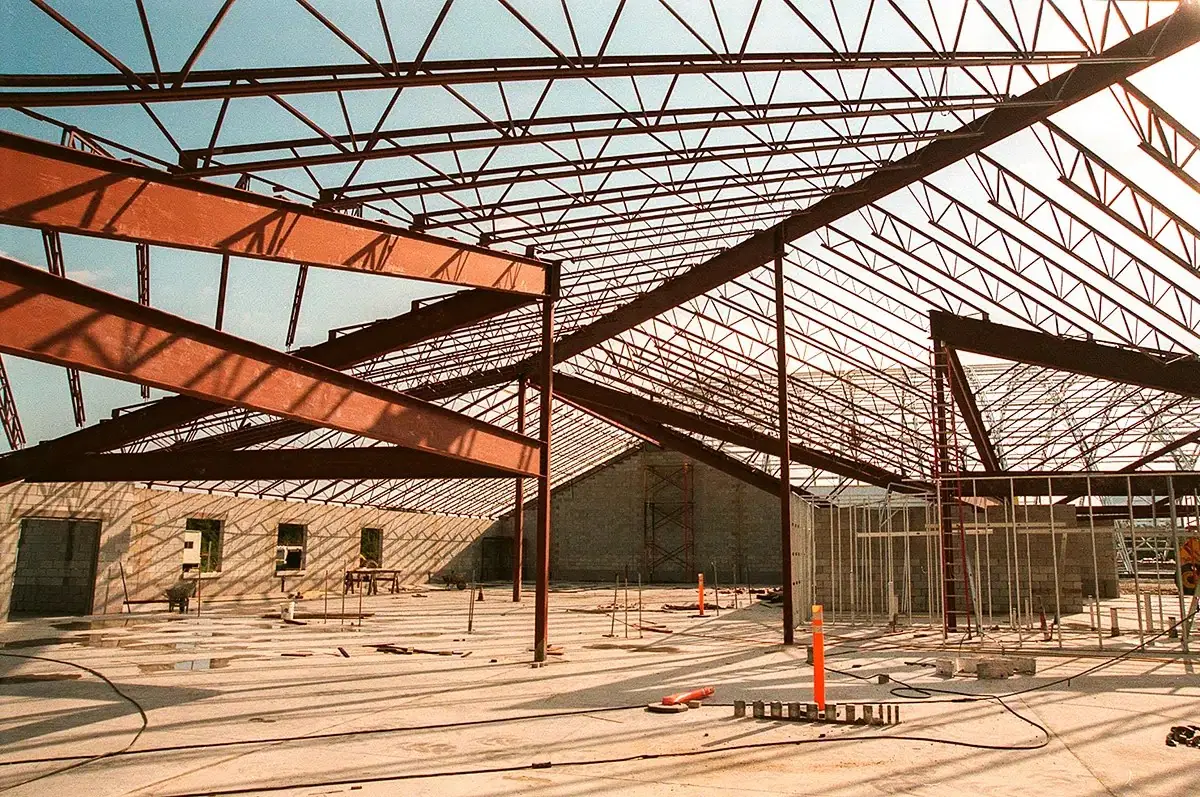 Poutres et fermes en acier d’un bâtiment en construction, ombres portées au sol